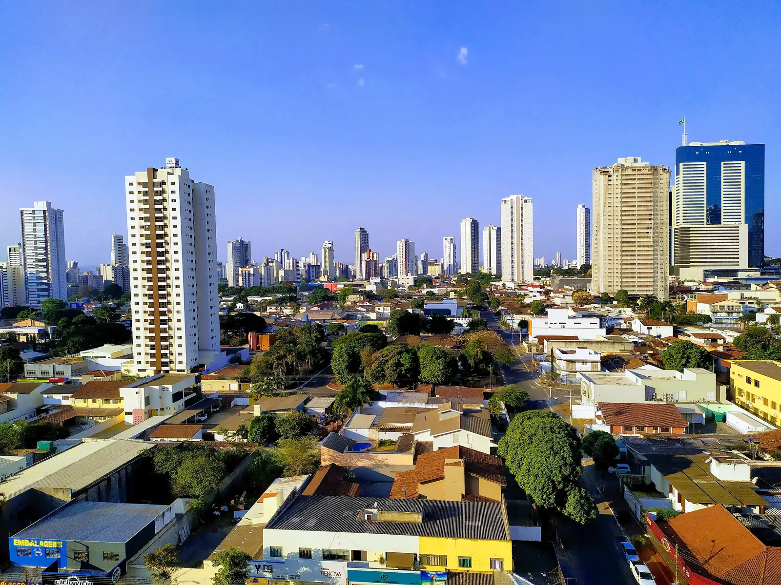 Vista de Goiânia com prédios altos e casas sob céu azul