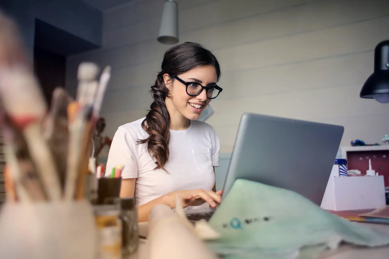 Mulher de óculos trabalhando no notebook, enviando e recebendo arquivos com upload e download