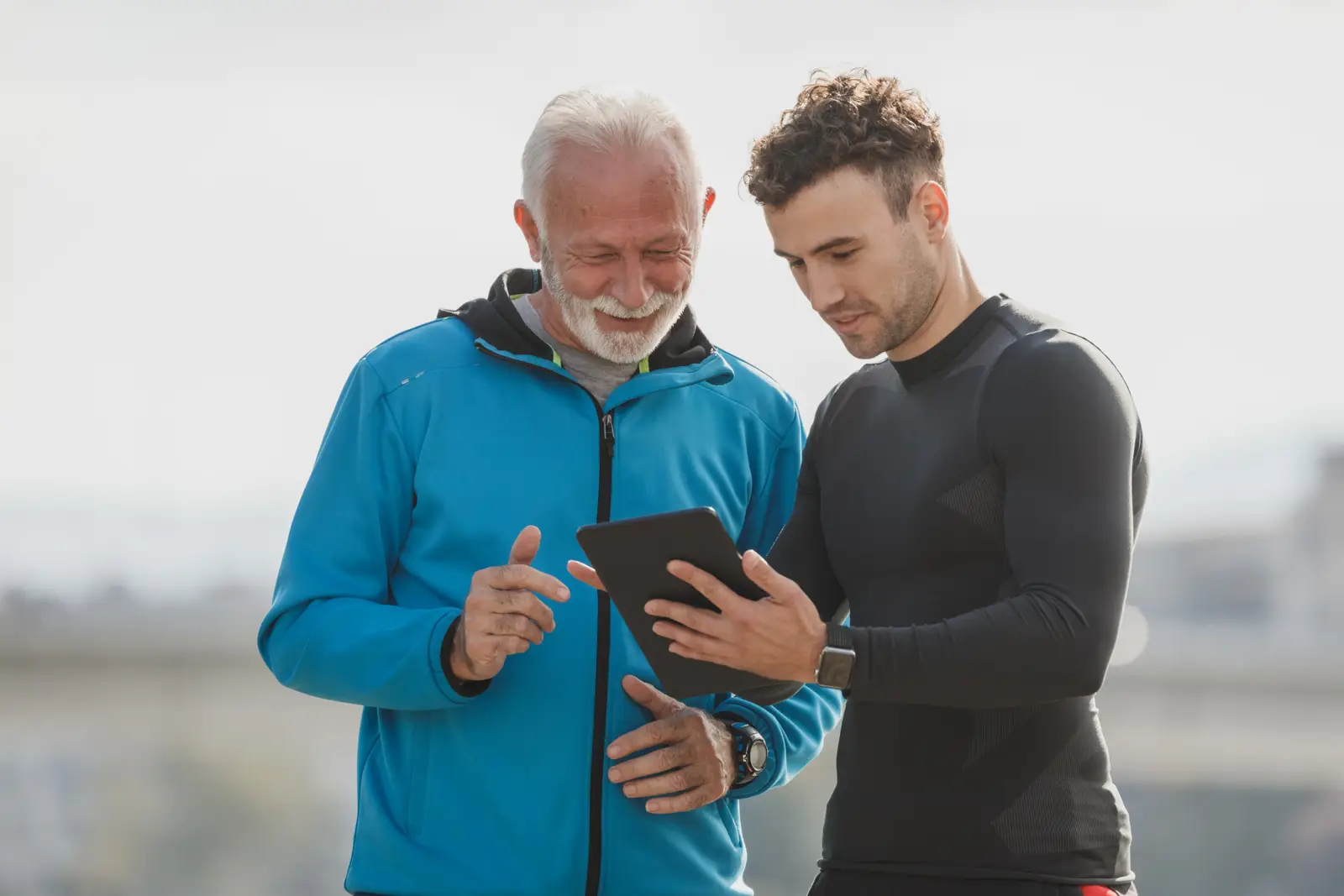 Senhor e jovem olhando o tablet juntos, comparando um combo internet e celular